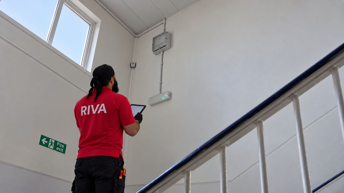 Riva Corporation engineer checking emergency lighting in a school stairwell